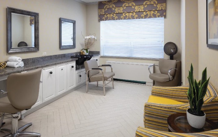 A cozy salon interior with chairs, a hair dryer, and a mirror by the window.