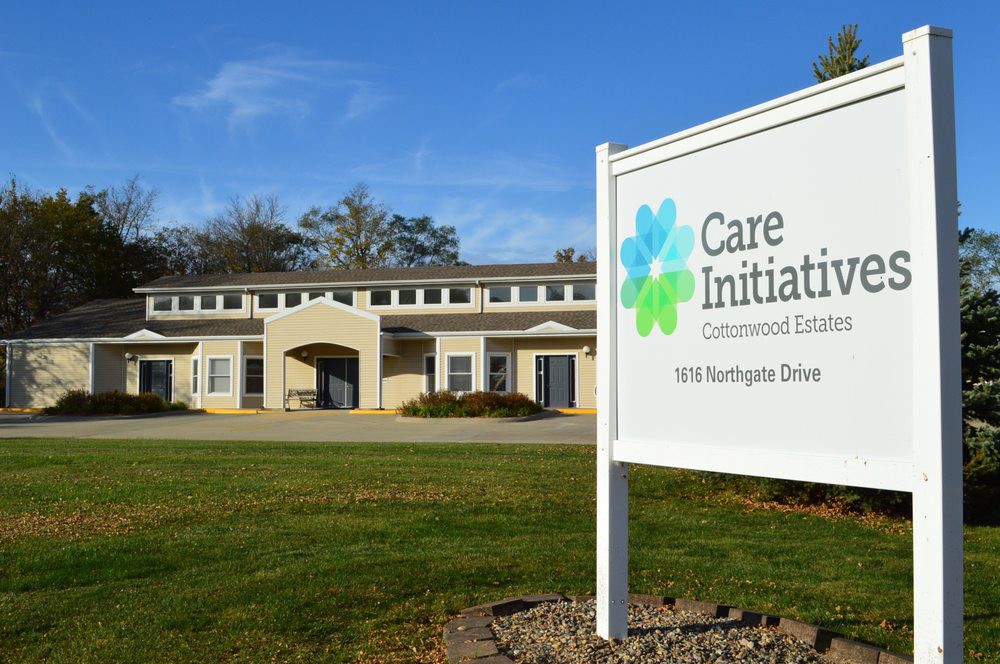 A care facility with its sign prominently displayed in front of a well-maintained lawn.