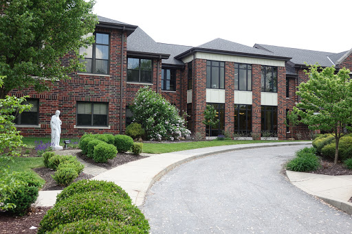 A modern brick building with landscaped surroundings and a curved driveway.