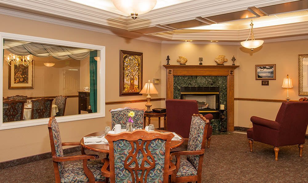 A cozy living room with a warm fireplace, ornate dining table, and traditional decor.
