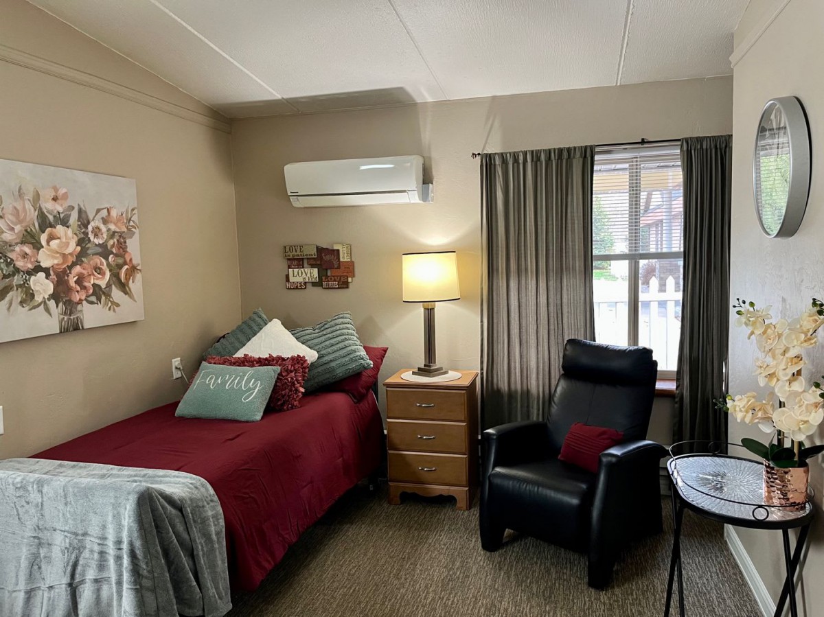 A cozy bedroom with a single bed, lamp, and comfortable chair by the window.