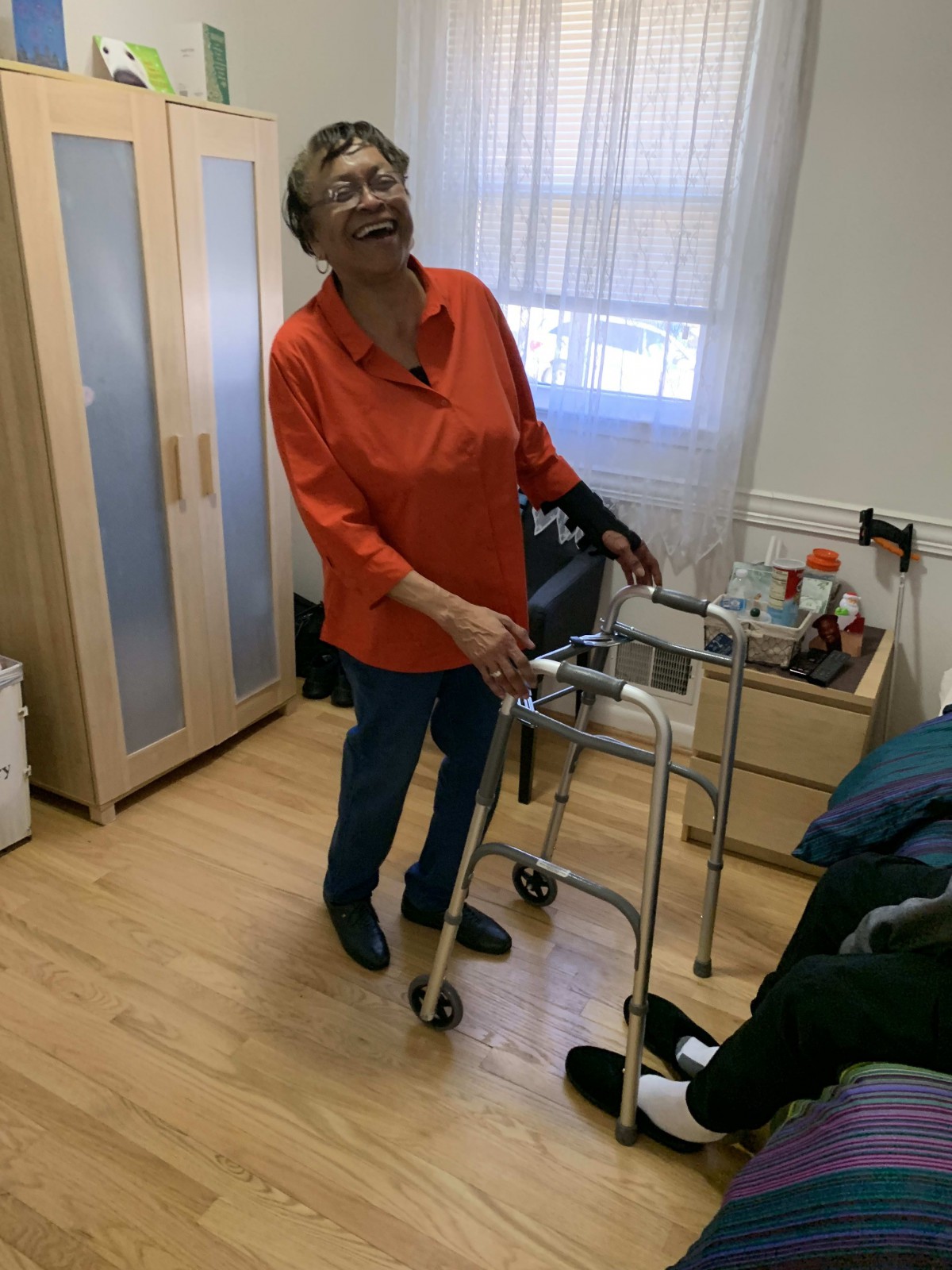 An elderly woman using a walker in a care home setting.