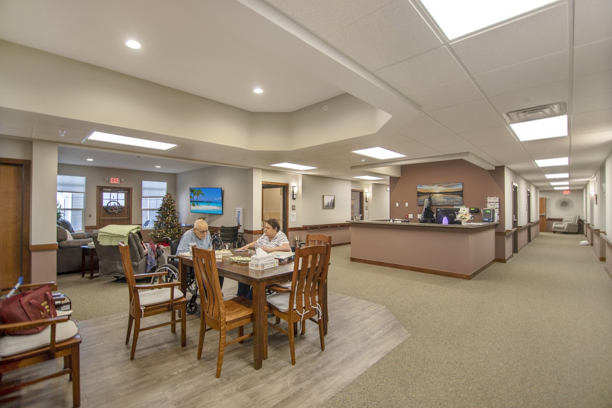 A welcoming lobby area with people seated around a table near the reception desk.