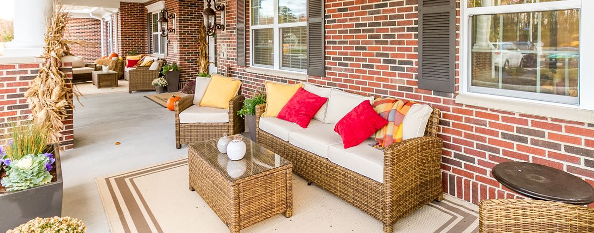A cozy outdoor patio with rattan furniture and vibrant cushions.