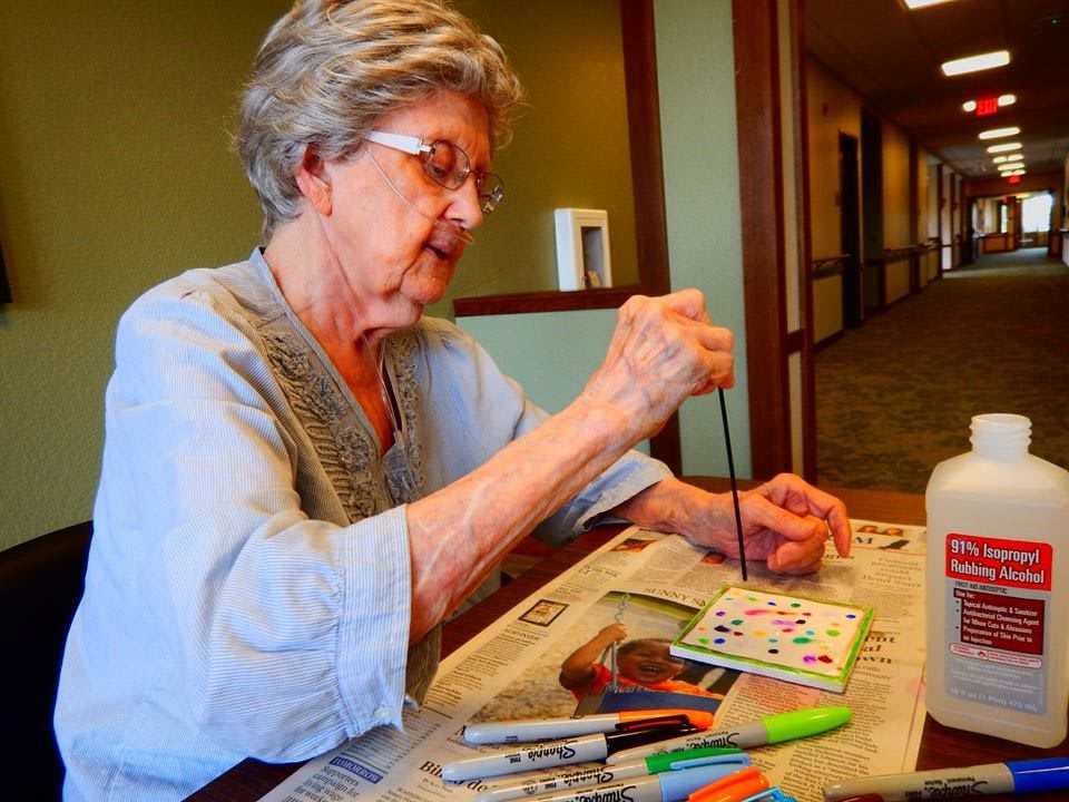 An elderly woman engaged in painting as a creative hobby indoors.
