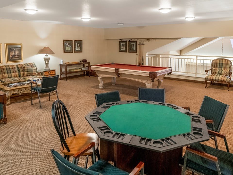 A cozy game room featuring a pool table and a poker table, designed for leisure and entertainment.