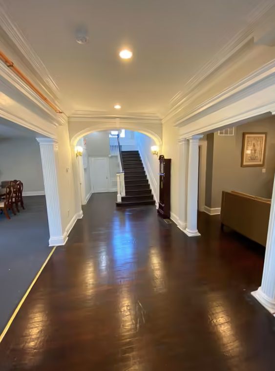 A spacious hallway with dark wood flooring and an archway leading to a staircase.
