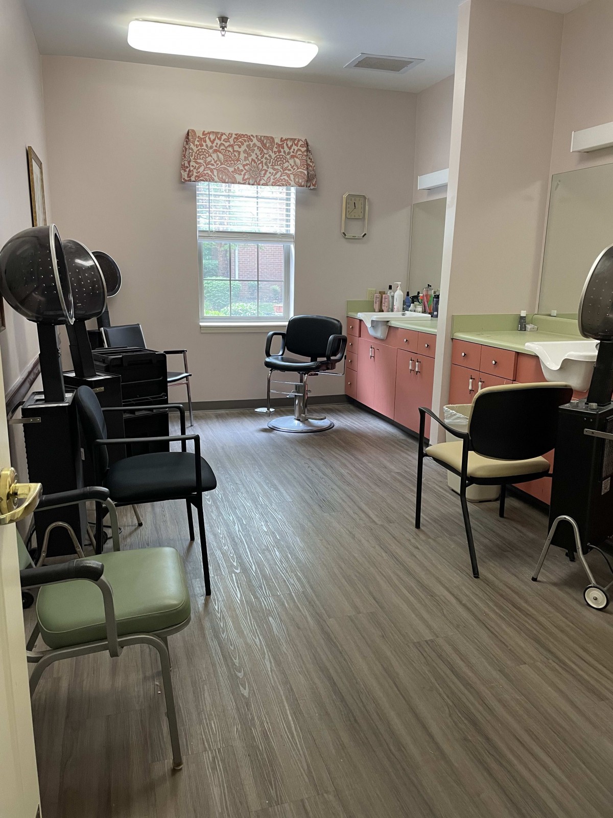 An empty hair salon with chairs, dryers, and mirrors.