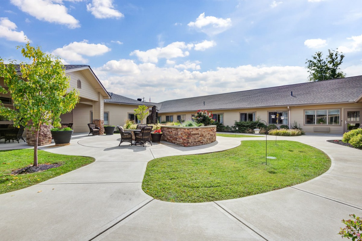 A well-maintained courtyard with a seating area and surrounding buildings under a blue sky.