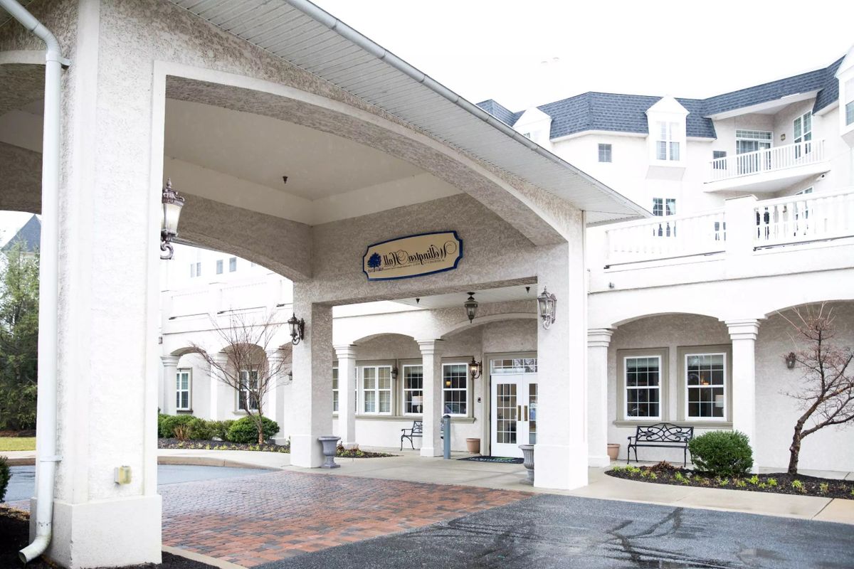 The front entrance of a white building with an awning and multiple windows.