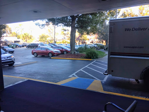 A view of a parking lot with several cars and trees in the background.
