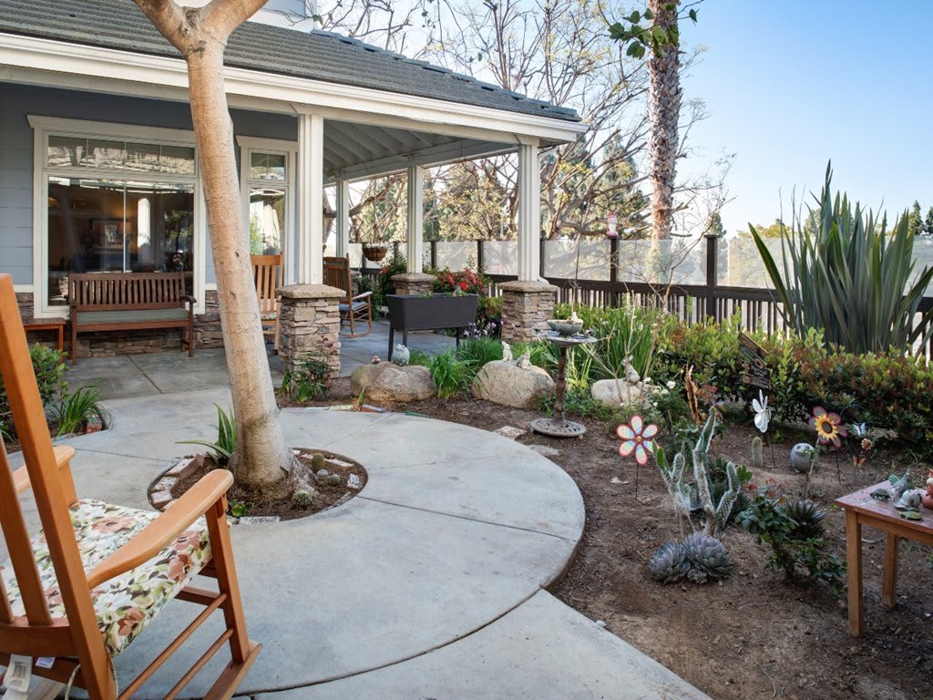 A cozy outdoor patio with a garden, featuring comfortable seating and lush landscaping.