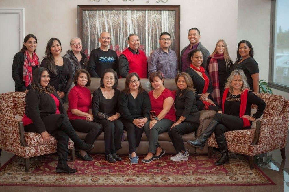 A group of people posing together in a formal setting, wearing red and black outfits.