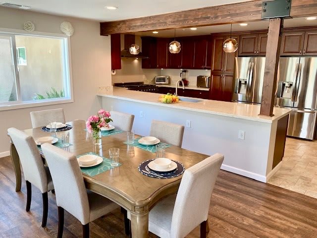 A modern kitchen and dining area with an open layout, featuring wooden floors and stylish furniture.