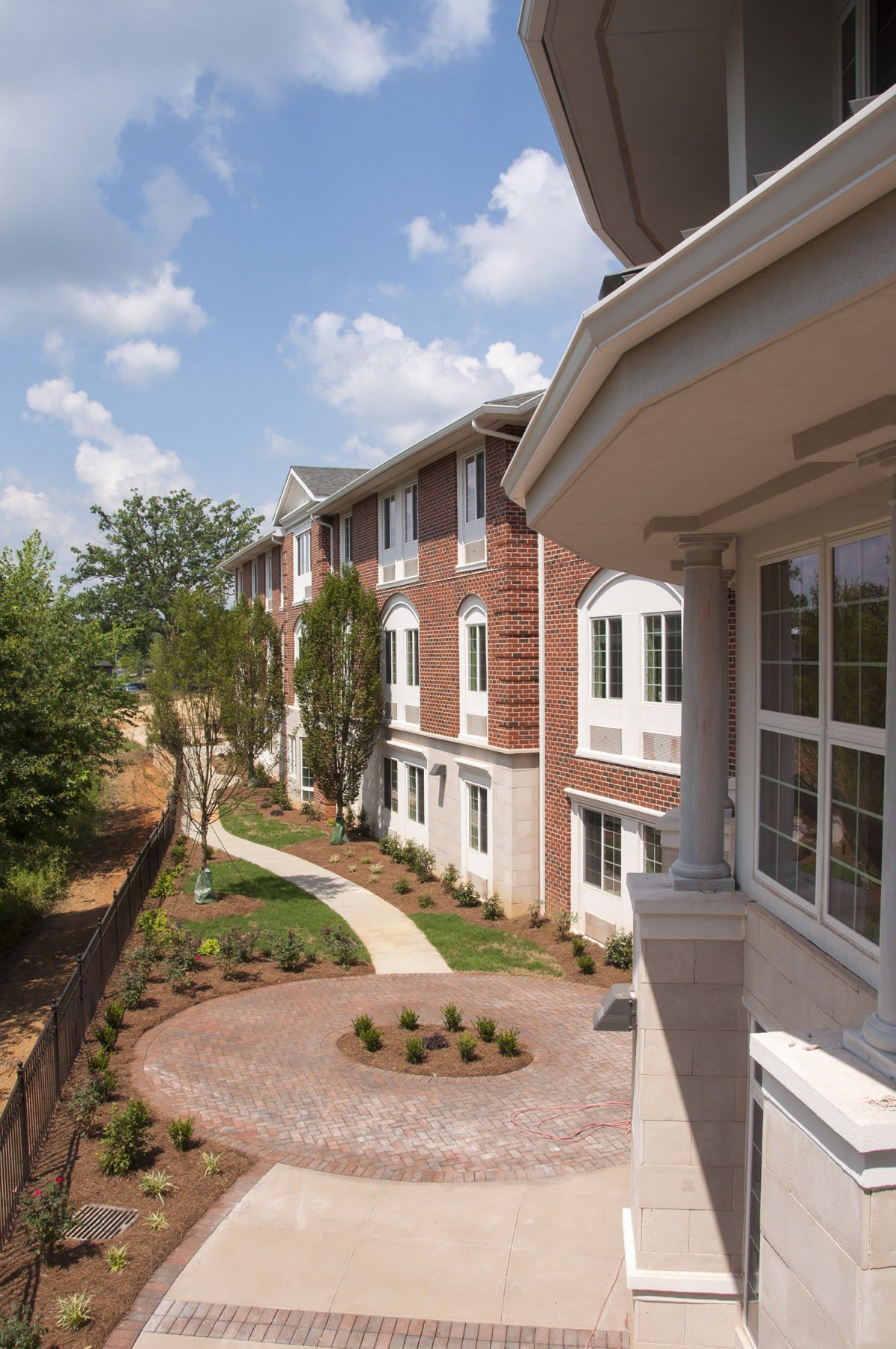 A view of a residential building with landscaped surroundings and a clear sky.