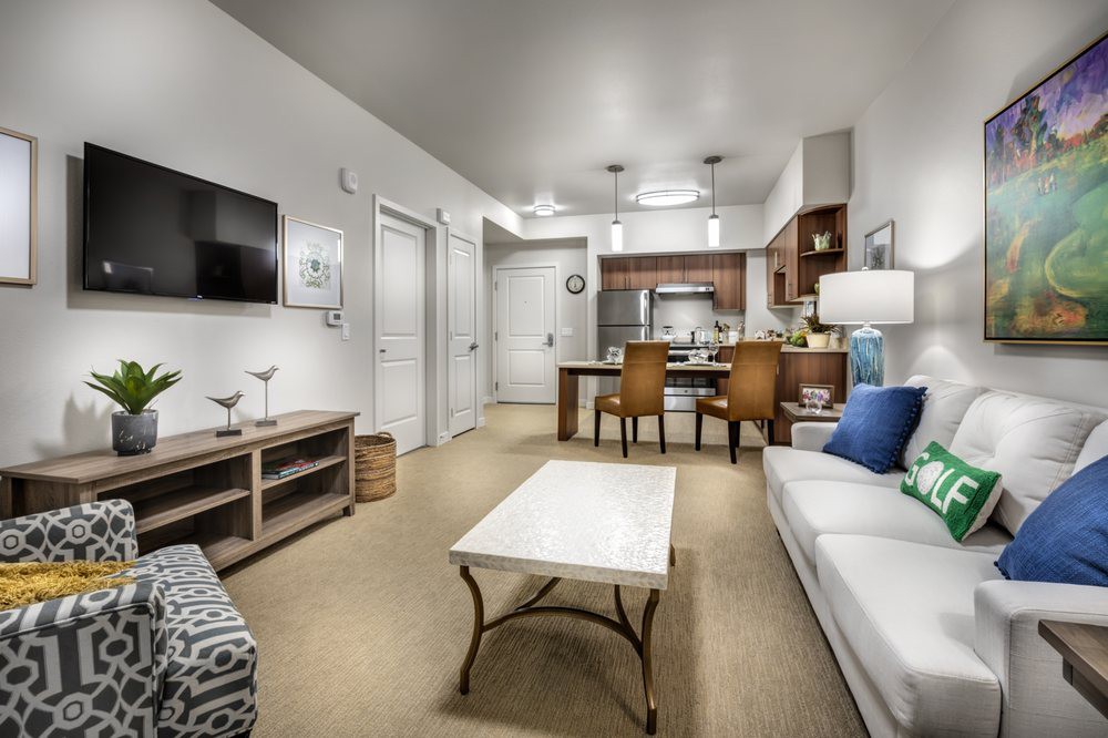 A modern living room and kitchen area in an apartment, featuring contemporary furniture and decor.