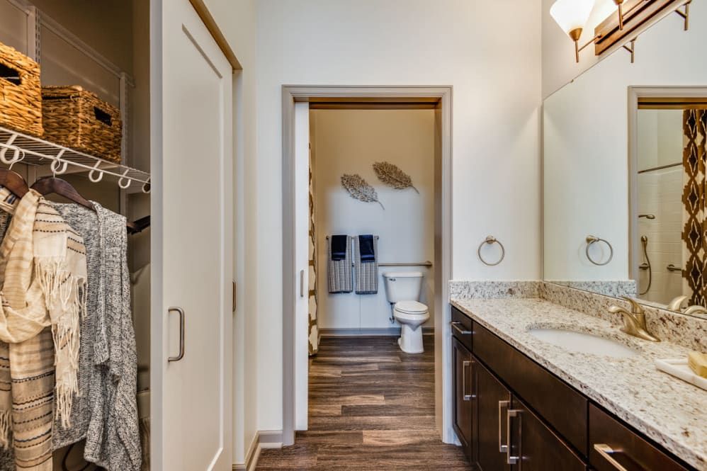 A modern bathroom with a view of the toilet area, featuring a wide countertop with a sink and mirror.