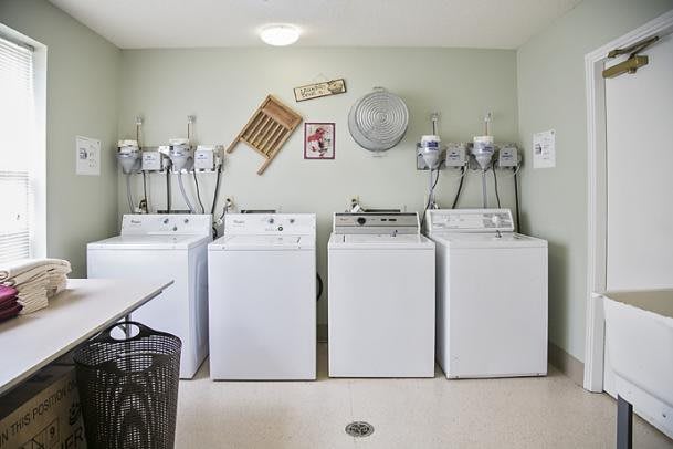 A well-organized laundry room with four washing machines lined up against the wall.