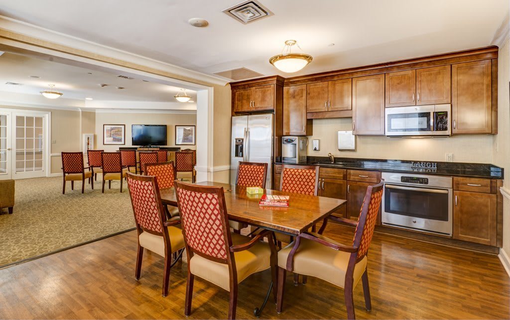 A well-furnished dining area with a wooden table and chairs, adjacent to a kitchen with wooden cabinets and modern appliances.