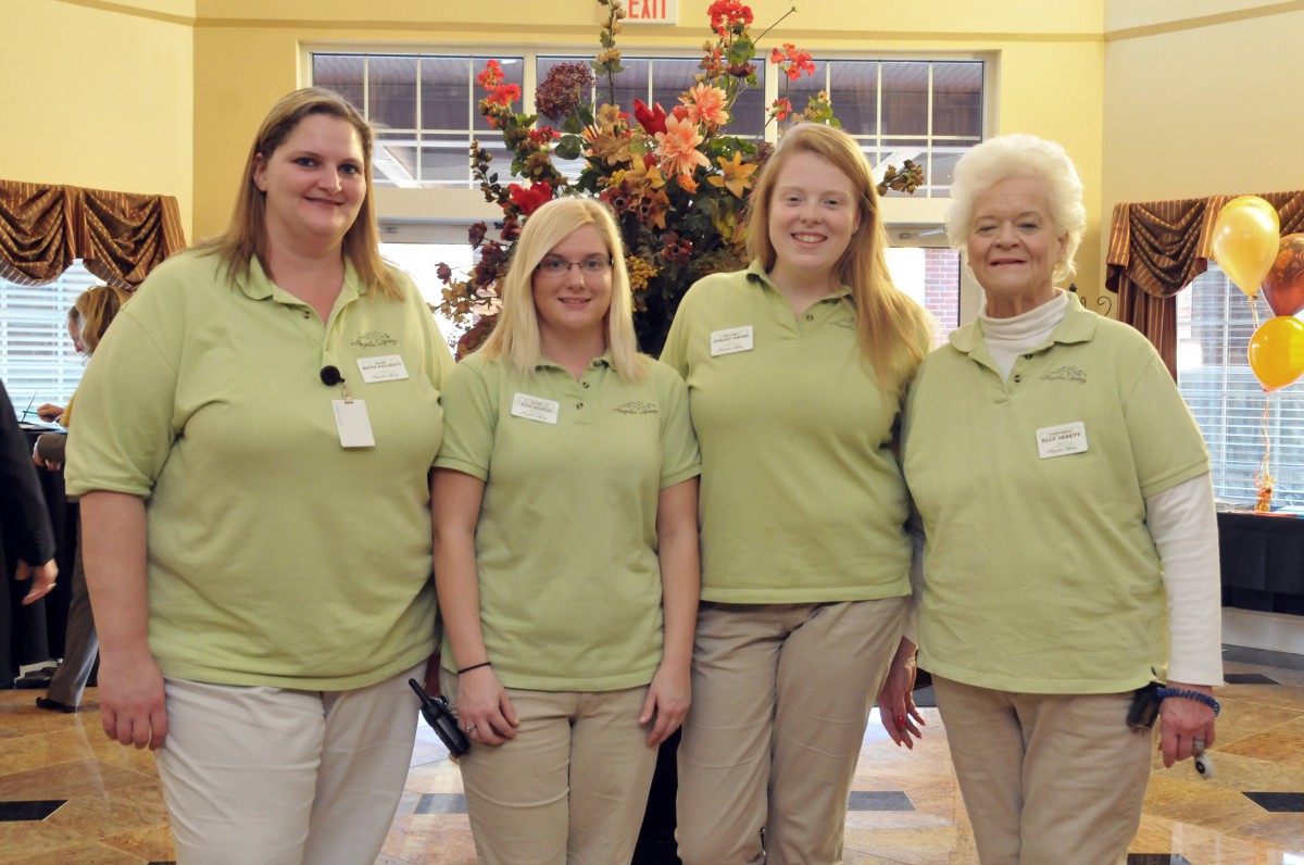 A group of four women in matching uniforms posing together at a workplace.