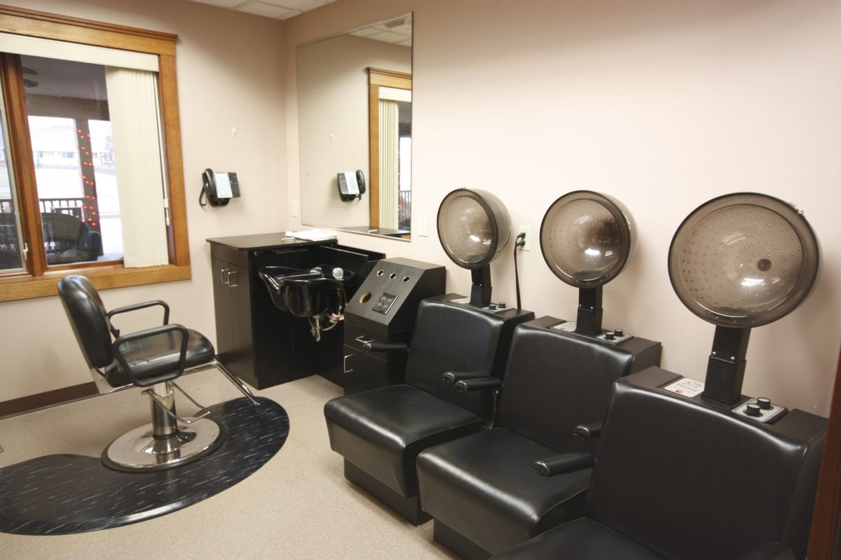 An empty hair salon featuring chairs and hooded hair dryers.