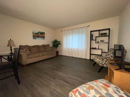 A cozy living room setup with a comfortable sofa, bookshelves, and natural light streaming through the window.
