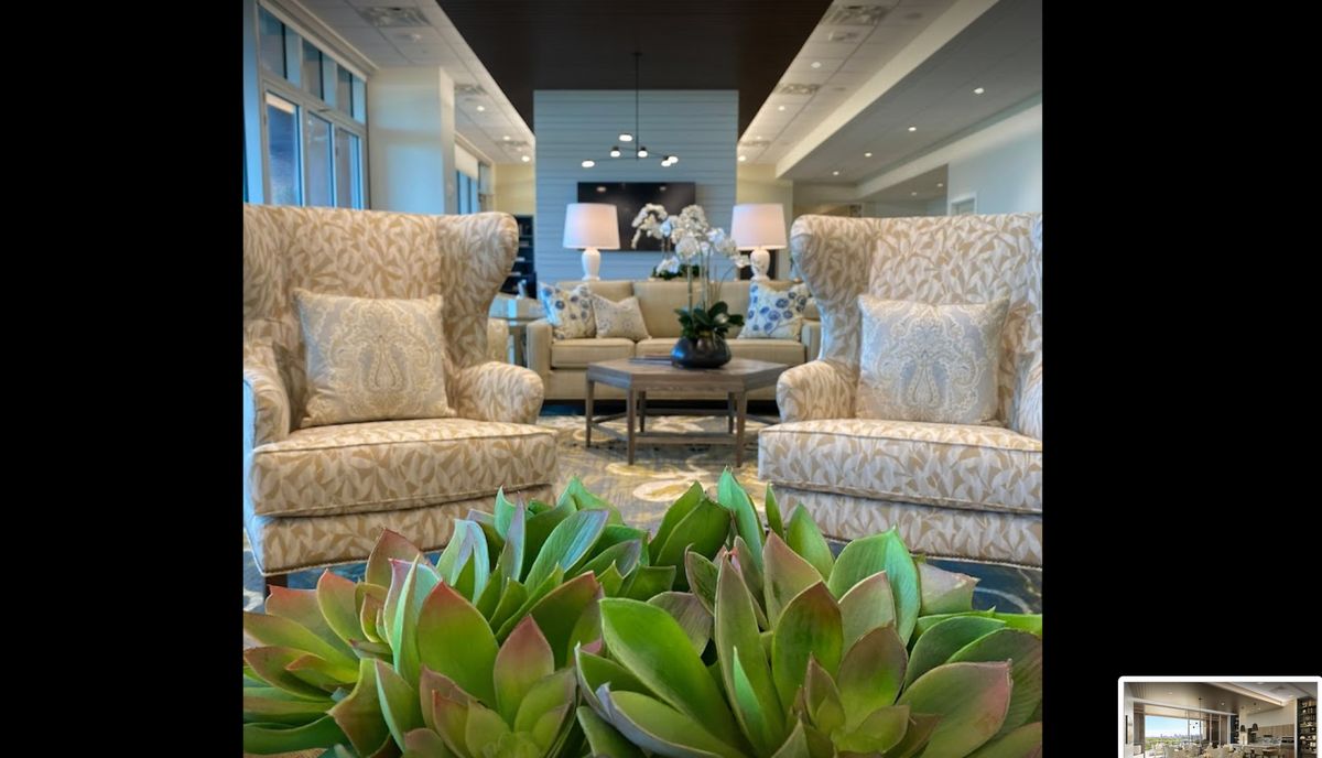 A luxurious lounge area with elegant armchairs, a sofa, and decorative plants.