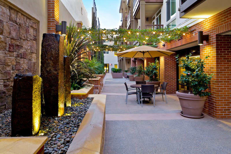 A charming outdoor patio with seating, string lights, and lush greenery in an urban environment.