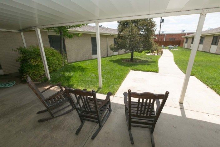 A peaceful patio with rocking chairs overlooking a garden walkway.