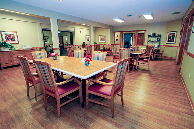 A spacious dining area featuring wooden tables and chairs, adorned with floral centerpieces.