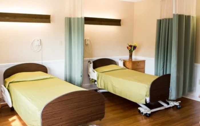 A clean and tidy hospital room with two beds separated by curtains.