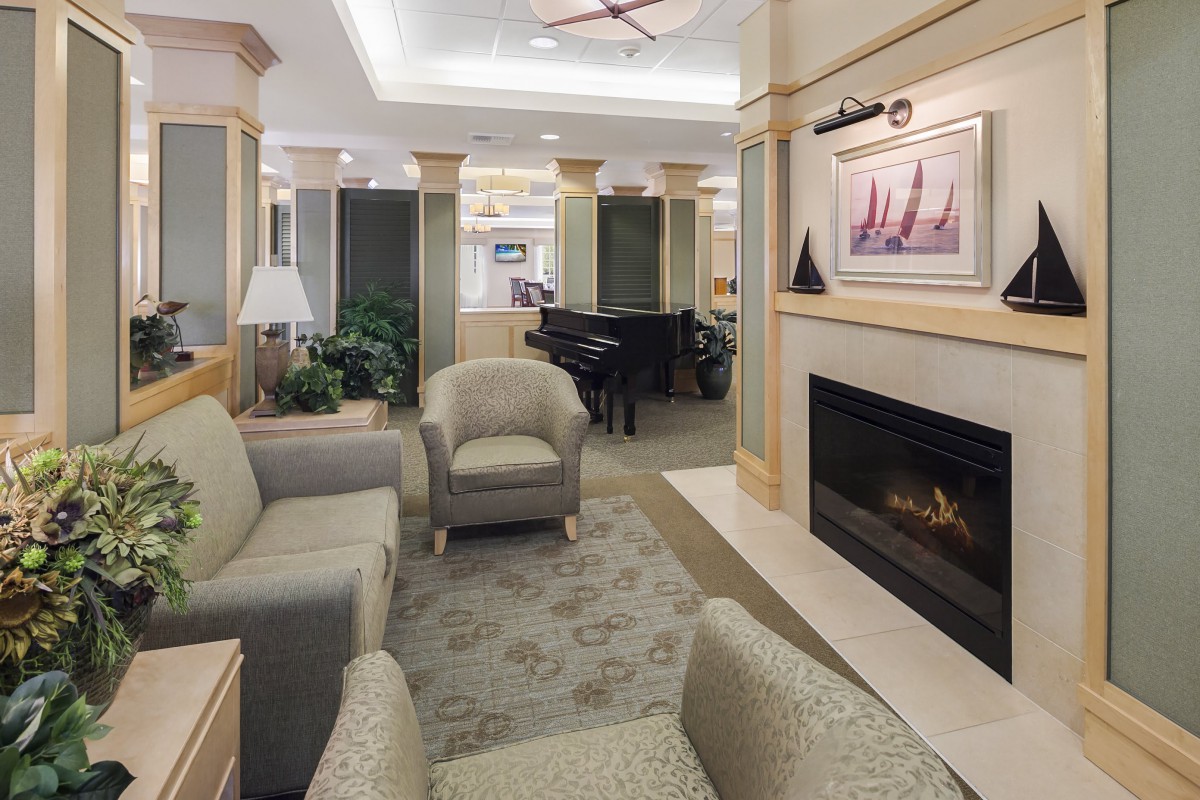 A cozy lounge area featuring comfortable seating, a fireplace, and a grand piano.