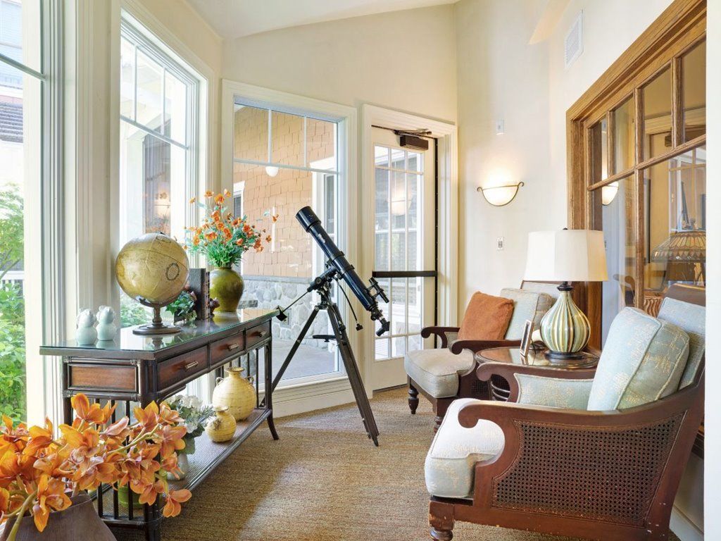 A cozy living room with a telescope by the window, featuring comfortable seating, decorative items, and a globe.