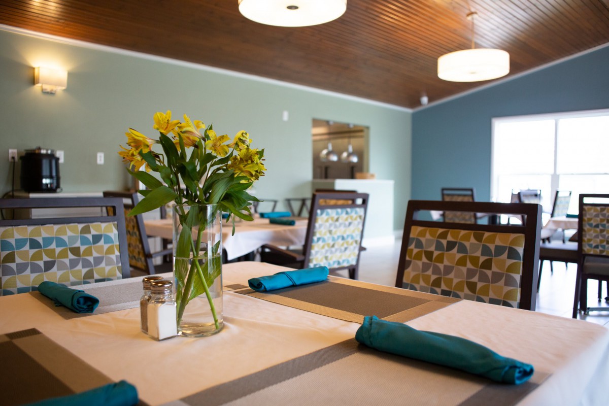 A cozy dining area with neatly arranged tables and a vase of flowers.