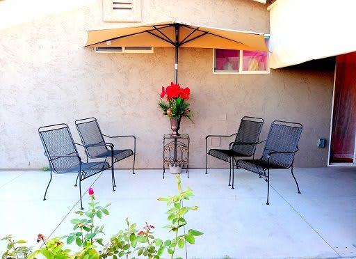 A cozy patio setup with chairs and an umbrella, adorned with flowers.