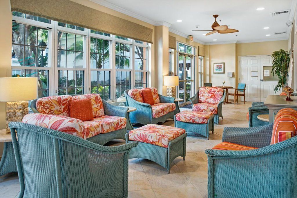 A bright and inviting living room with colorful wicker furniture and large windows.
