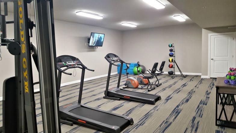 A small fitness room equipped with treadmills, dumbbells, and other exercise equipment.