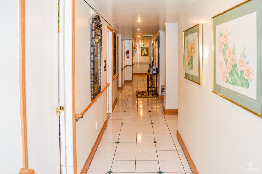 A well-lit hotel corridor with tiled flooring and decorative paintings on the walls.
