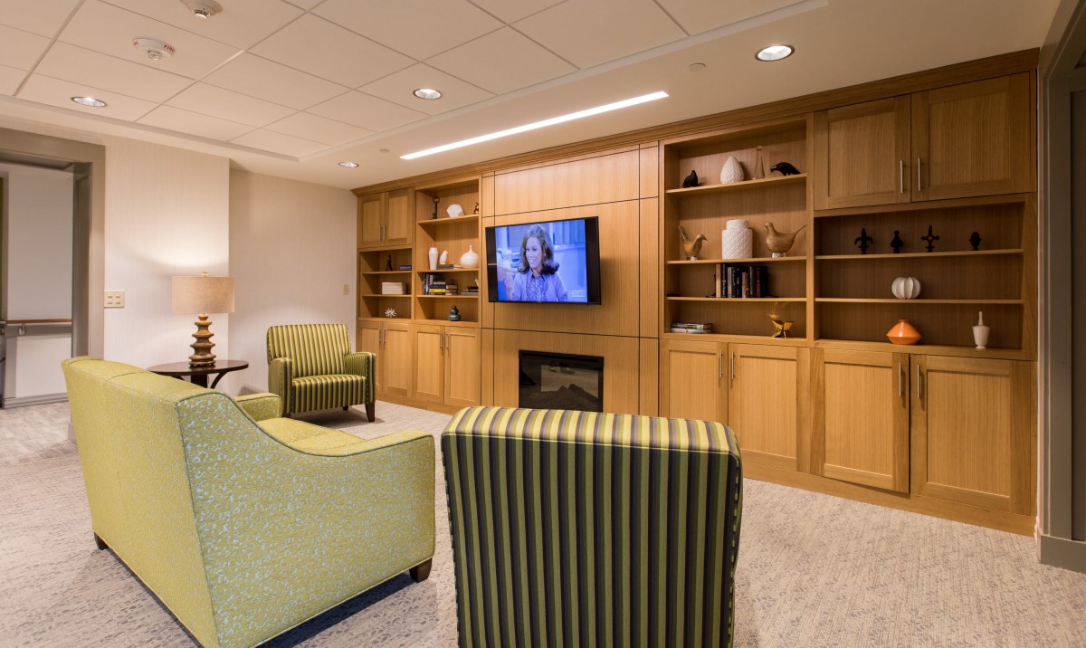 A cozy living room with comfortable seating, a television, and built-in bookshelves surrounding a fireplace.