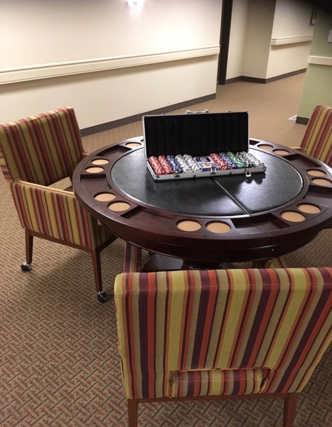 A poker table set with cards and chips, surrounded by striped chairs.