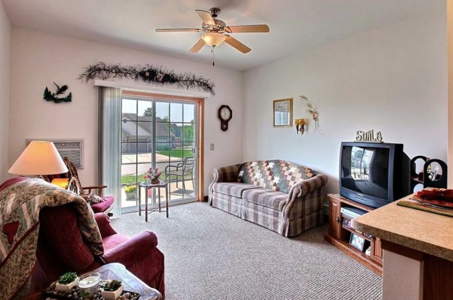 A cozy living room with a sofa, television, and a ceiling fan.