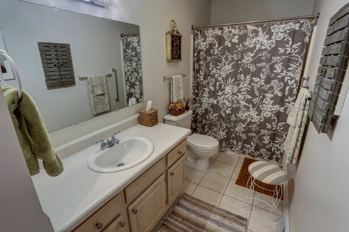 A well-organized bathroom with a floral shower curtain and neatly arranged decor.