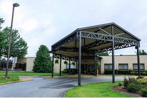 A building entrance with a large canopy and surrounding greenery.