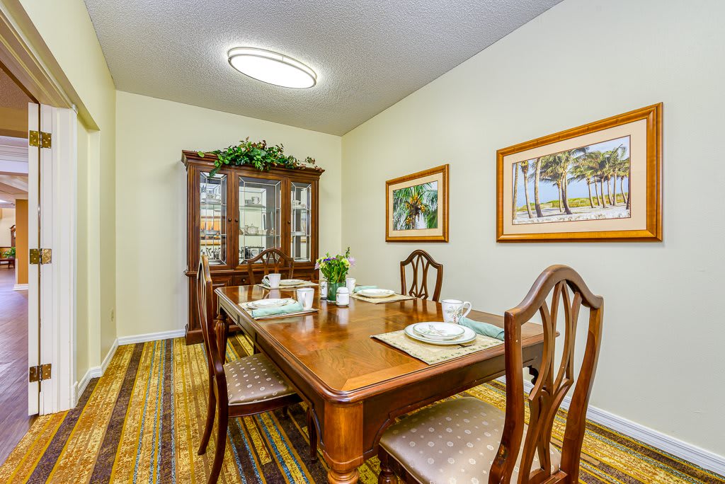 A cozy dining room featuring a wooden table, chairs, and a china cabinet adorned with decorative items and artwork on the walls.