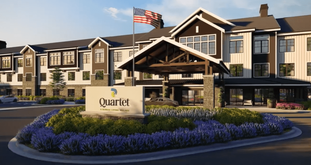 A modern residential building with landscaped surroundings and an American flag on display.