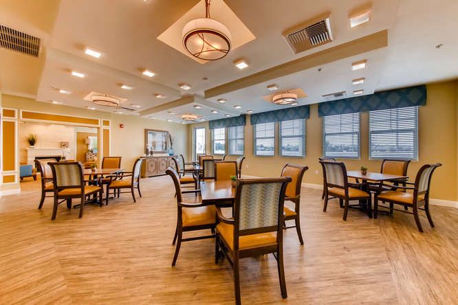 A well-lit dining area featuring multiple tables and chairs, with modern lighting and wooden flooring.