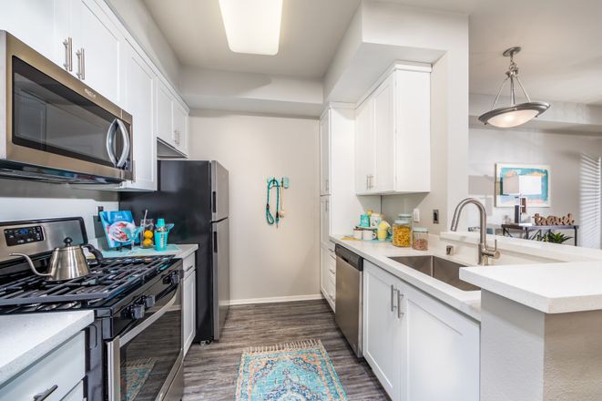 A modern kitchen with white cabinets and stainless steel appliances.
