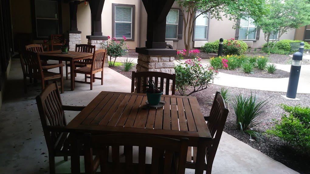 A cozy outdoor patio area featuring wooden furniture and lush garden landscaping.