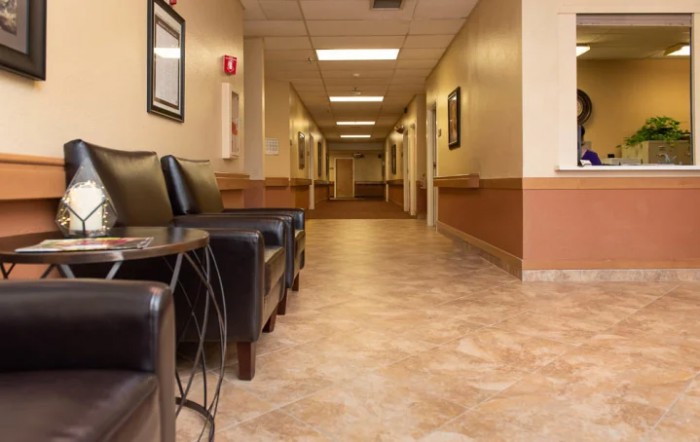 A quiet hospital hallway with chairs in the waiting area.