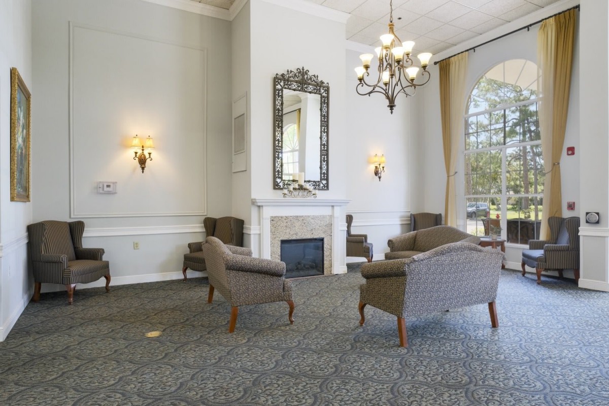 A cozy lounge area with armchairs arranged around a fireplace and chandelier lighting.